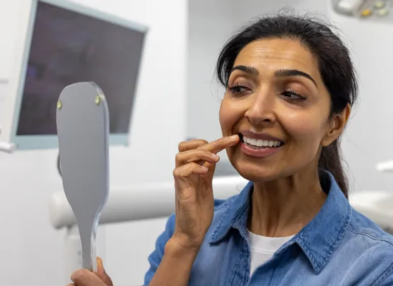 Woman examining her gums in a mirror